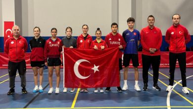 Özel Sporcular Para Masa Tenisi Millî Takımı ile teknik ekip beraber spor salonunda Türk bayrağıyla poz veriyor.