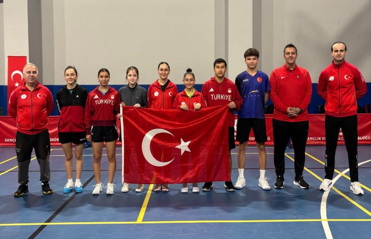 Özel Sporcular Para Masa Tenisi Millî Takımı ile teknik ekip beraber spor salonunda Türk bayrağıyla poz veriyor.