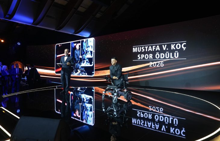 2026 Mustafa V. Koç Spor Ödülü’nün sahibi olan Para Milli yüzücü Umut Ünlü, tören sahnesinde tekerlekli sandalyesiyle yer alırken, ödül anına eşlik eden sunucu ve arka plandaki görsel ekranda ödülün adı ile yılı dikkat çekiyor.