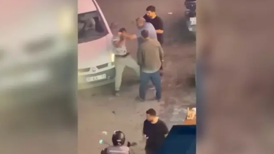 Görselin üst bölümünde, akşam saatlerinde sokak lambaları altında gerçekleşen darp anına ait güvenlik kamerası veya cep telefonu kaydı perspektifi yer alıyor. Beyaz bir hafif ticari aracın önünde duran açık renk kıyafetli engelli seyyar satıcıya doğru yönelen ve onu tartaklayan şüpheli ile araya girmeye çalışan çevredeki kişiler görülüyor. Ön planda kasklı bir motosiklet sürücüsü ve yoldan geçen diğer vatandaşlar kadrajda dikkat çekiyor.