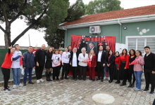 Görselde, tek katlı bir binanın önündeki bahçede 29 Ekim Cumhuriyet Bayramı kutlaması için bir araya gelmiş kalabalık bir grup insan yer almaktadır. Arkalarındaki duvarda Atatürk posteri, Türk bayrakları ve kırmızı süslemeler bulunan bir pano yer alırken, katılımcıların bir kısmı ellerinde Türk bayrakları tutarak poz vermektedir.