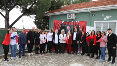 Görselde, tek katlı bir binanın önündeki bahçede 29 Ekim Cumhuriyet Bayramı kutlaması için bir araya gelmiş kalabalık bir grup insan yer almaktadır. Arkalarındaki duvarda Atatürk posteri, Türk bayrakları ve kırmızı süslemeler bulunan bir pano yer alırken, katılımcıların bir kısmı ellerinde Türk bayrakları tutarak poz vermektedir.