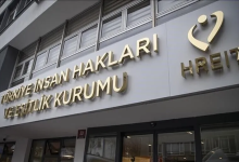 Görselin üst bölümünde, Türkiye İnsan Hakları ve Eşitlik Kurumu (TİHEK) hizmet binasının dış cephesi alttan ve açılı bir perspektifle yer alıyor. Açık gri renkli cephe paneli üzerinde altın sarısı kabartma harflerle Türkçe olarak "TÜRKİYE İNSAN HAKLARI VE EŞİTLİK KURUMU" yazısı, sağında ise kurumun kalbi ve insanı simgeleyen altın sarısı logosu ile altında İngilizce kısaltması olan "HREIT" ibaresi görülüyor. Arka planda binanın modern pencereleri ve alt kısımda cam giriş kapısı dikkat çekiyor.