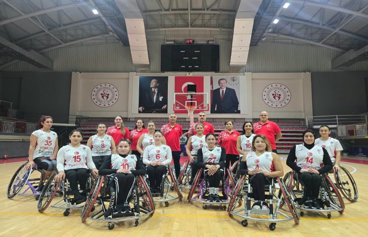 Tekerlekli Sandalye Basketbol Kadın Milli Takımımız önde, teknik heyet arkalarında bulunurken basketbol sahasında poz veriyorlar.
