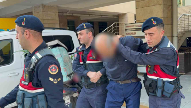 Instagram İçin Alternatif Metin: Görselin üst bölümünde, adliye binası önünde jandarma ekipleri tarafından kolları tutularak sevk edilen bir şüpheli yer alıyor. Mavi gömlek ve koyu renk pantolon giymiş olan şüphelinin yüzü mozaiklenerek gizlenmiş olup başı öne eğik vaziyettedir. Şüphelinin her iki yanında ve önünde, lacivert üniformalı, mavi bereli ve hücum yelekli jandarma personeli bulunuyor. Arka planda beyaz bir jandarma aracı, adliye binasının sütunları ile girişteki "CUMHURİYET BAŞSAVCILIĞI / MAHKEMELER" tabelası görülüyor.
